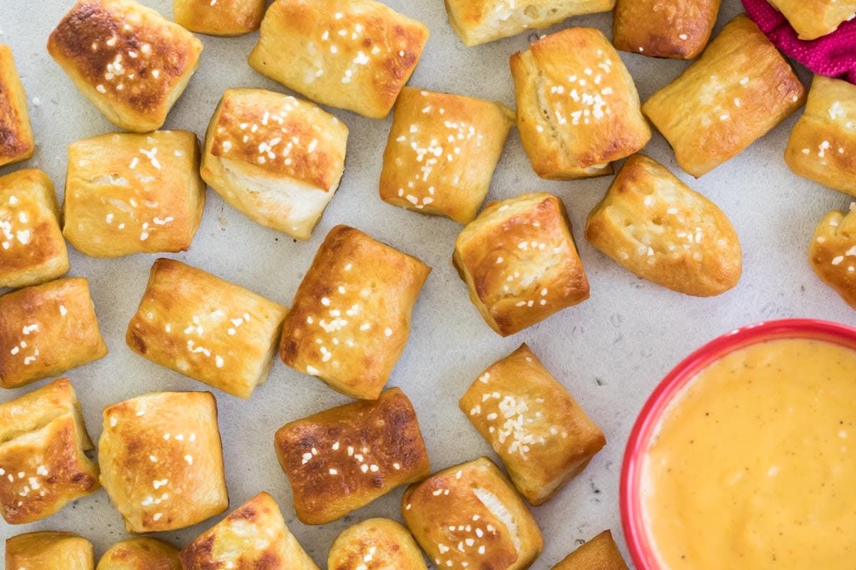top down view of golden brown homemade soft pretzel bites topped with salt and served with cheese dip