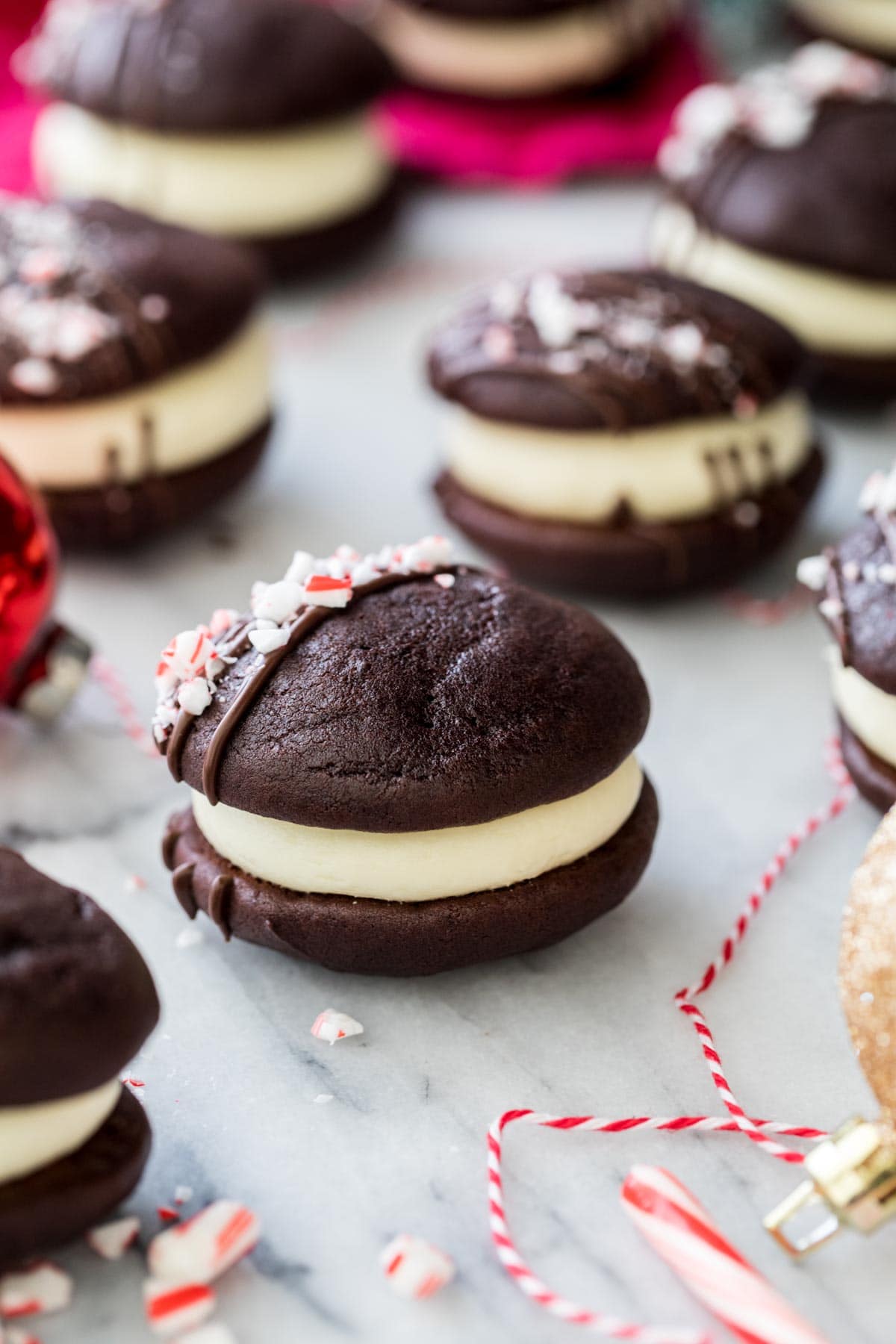 peppermint bark whoopie pies lined up on a white and gray marble surface