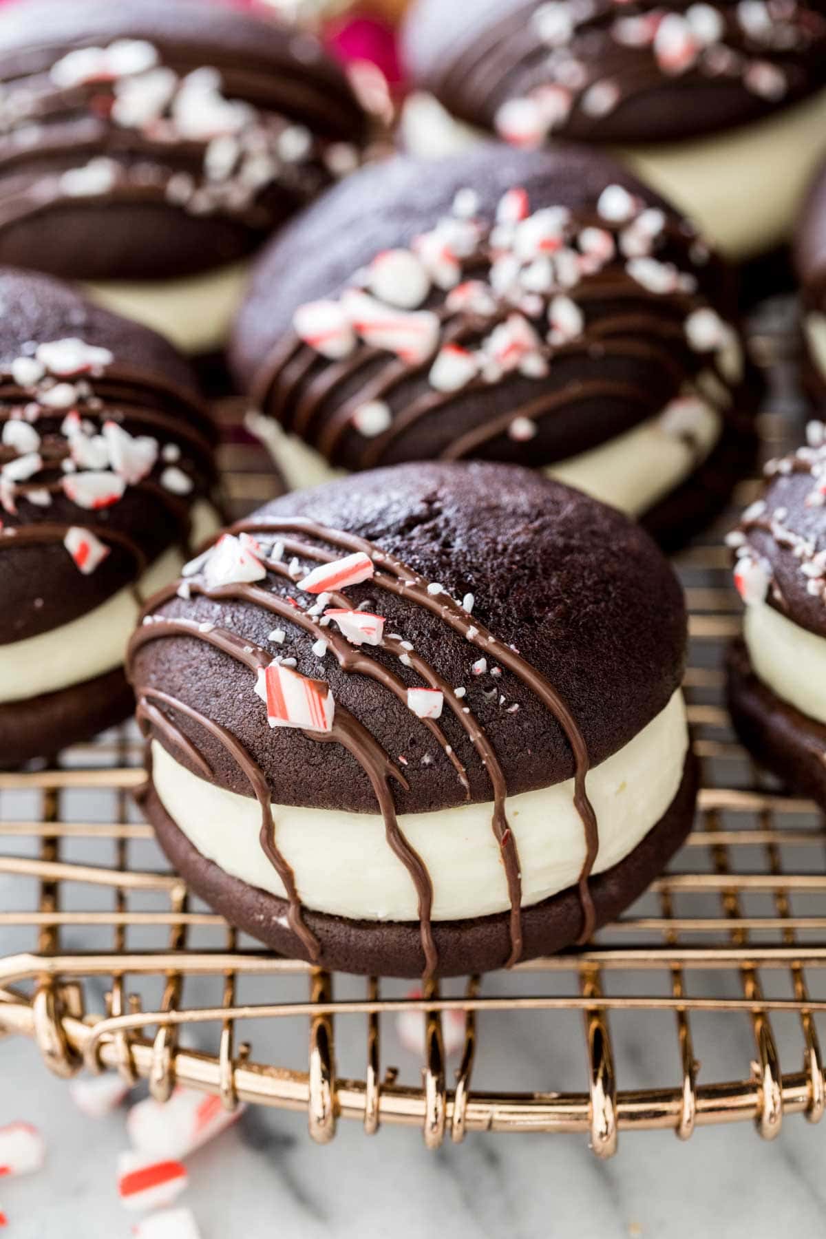 close-up view of a peppermint bark whoopie pie decorated with a melted chocolate drizzle and crushed candy canes