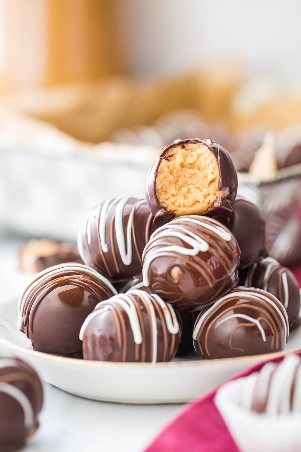 shiny chocolate coated peanut butter balls stacked on plate, with top ball missing a bite to show peanut butter center