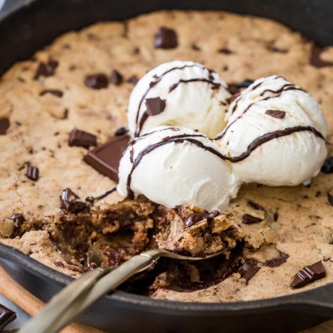 pizookie topped with vanilla ice cream being scooped into with a spoon