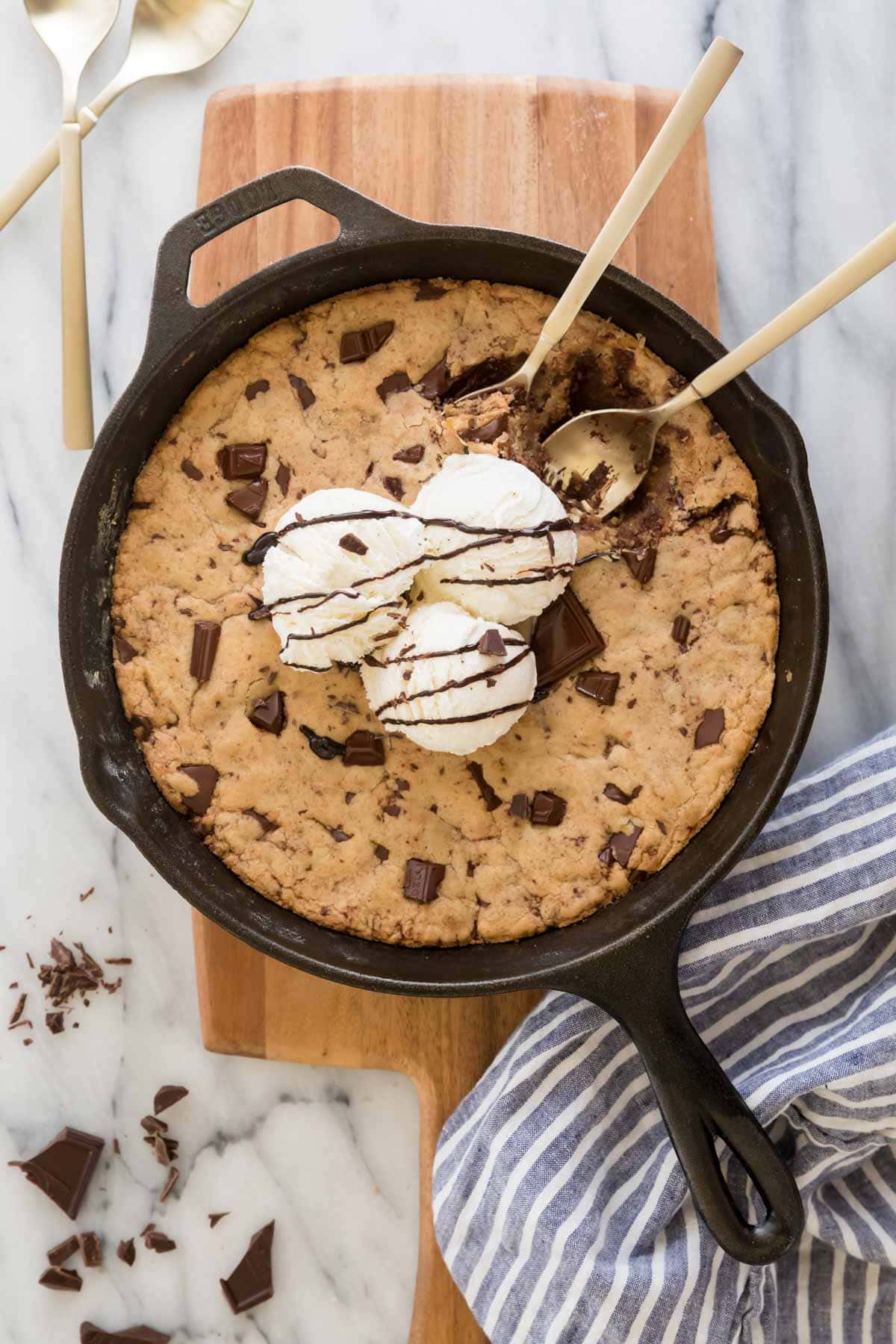 overhead view of pizookie in a cast iron skillet topped with vanilla ice cream and chocolate sauce