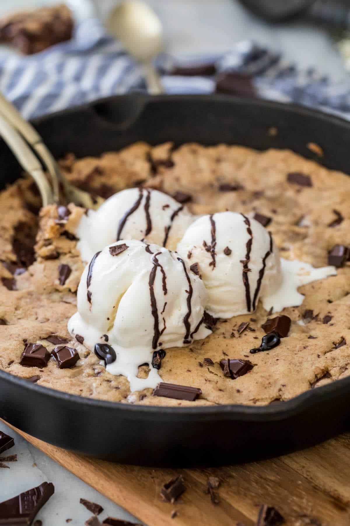three scoops of vanilla ice cream melting into a warm pizookie baked in a cast iron skillet
