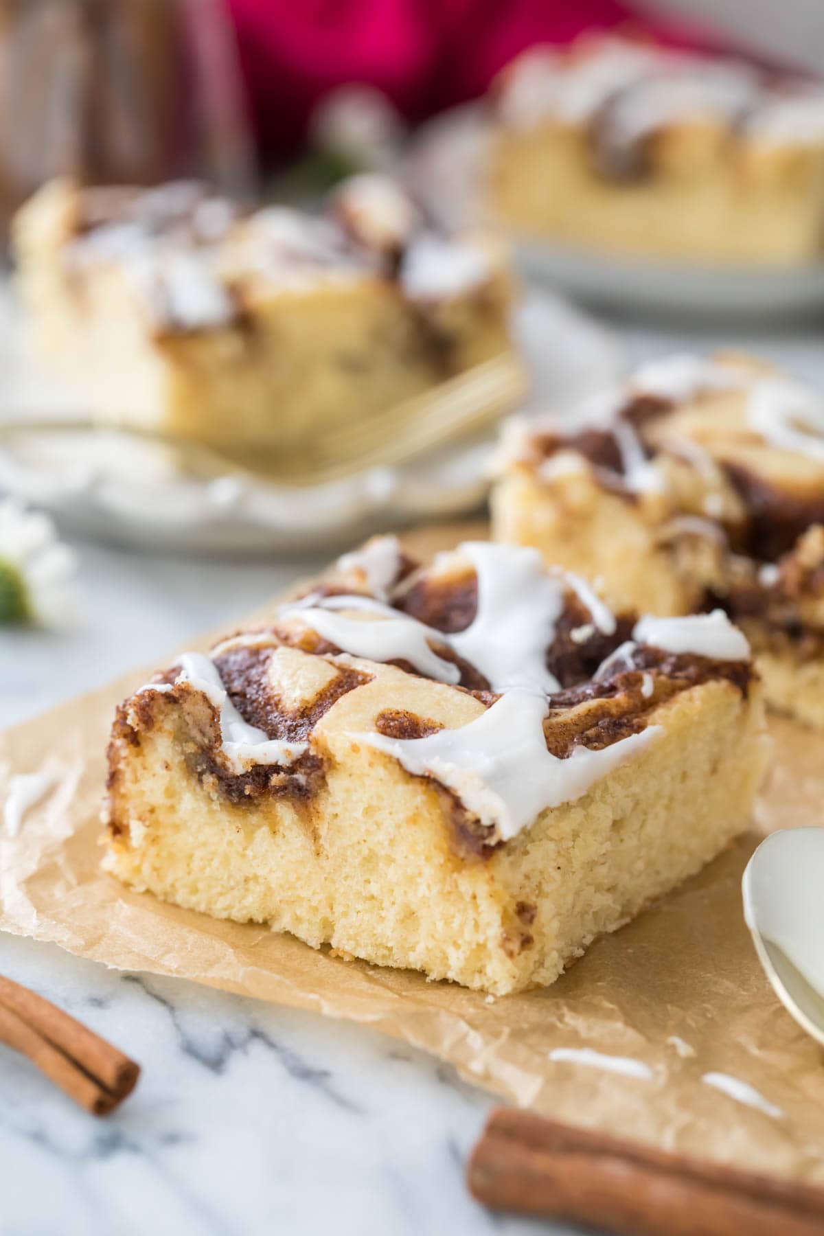 square slices of cinnamon roll cake swirled with cinnamon filling and drizzled with white icing