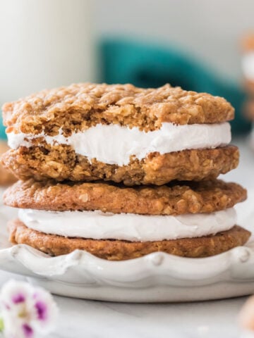 close-up view of two oatmeal cream pies stacked on top of each other on a white decorative plate, with the top cream pie missing a bite