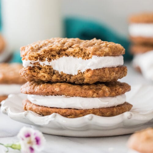 close-up view of two oatmeal cream pies stacked on top of each other on a white decorative plate, with the top cream pie missing a bite