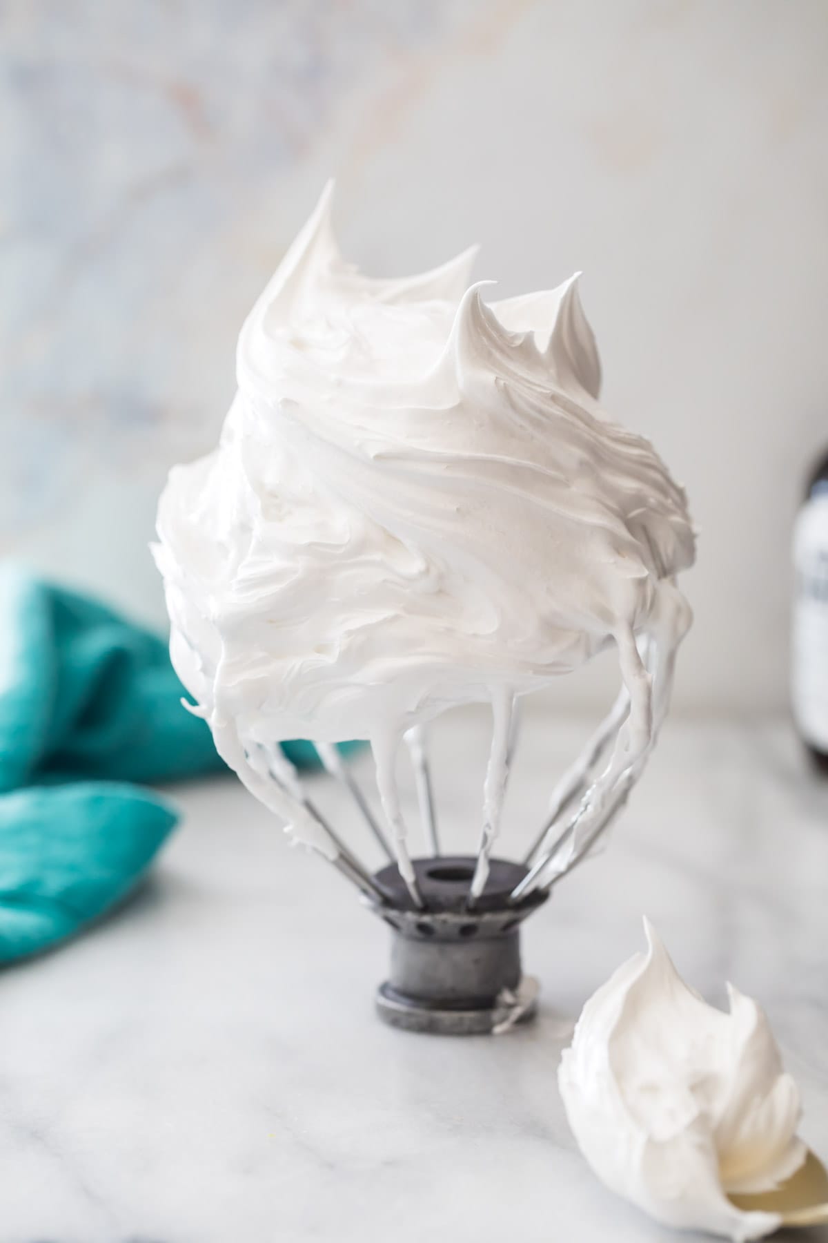 whisk attachment resting upside down on a counter to display stiff peaks in marshmallow cream filling for oatmeal cream pies