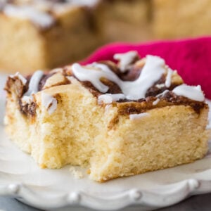 square slice of iced cinnamon roll cake that's missing one bite