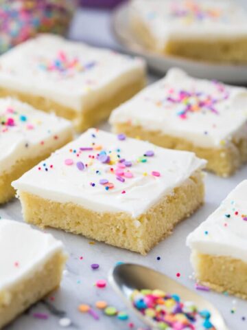square shaped frosted sugar cookie bars neatly arranged on white marble surface