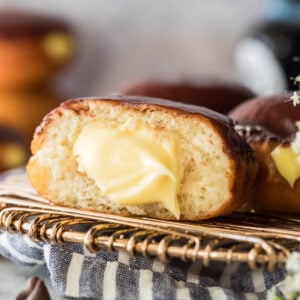 A ganache topped Boston cream donut that's been cut in half to show the pastry cream filling