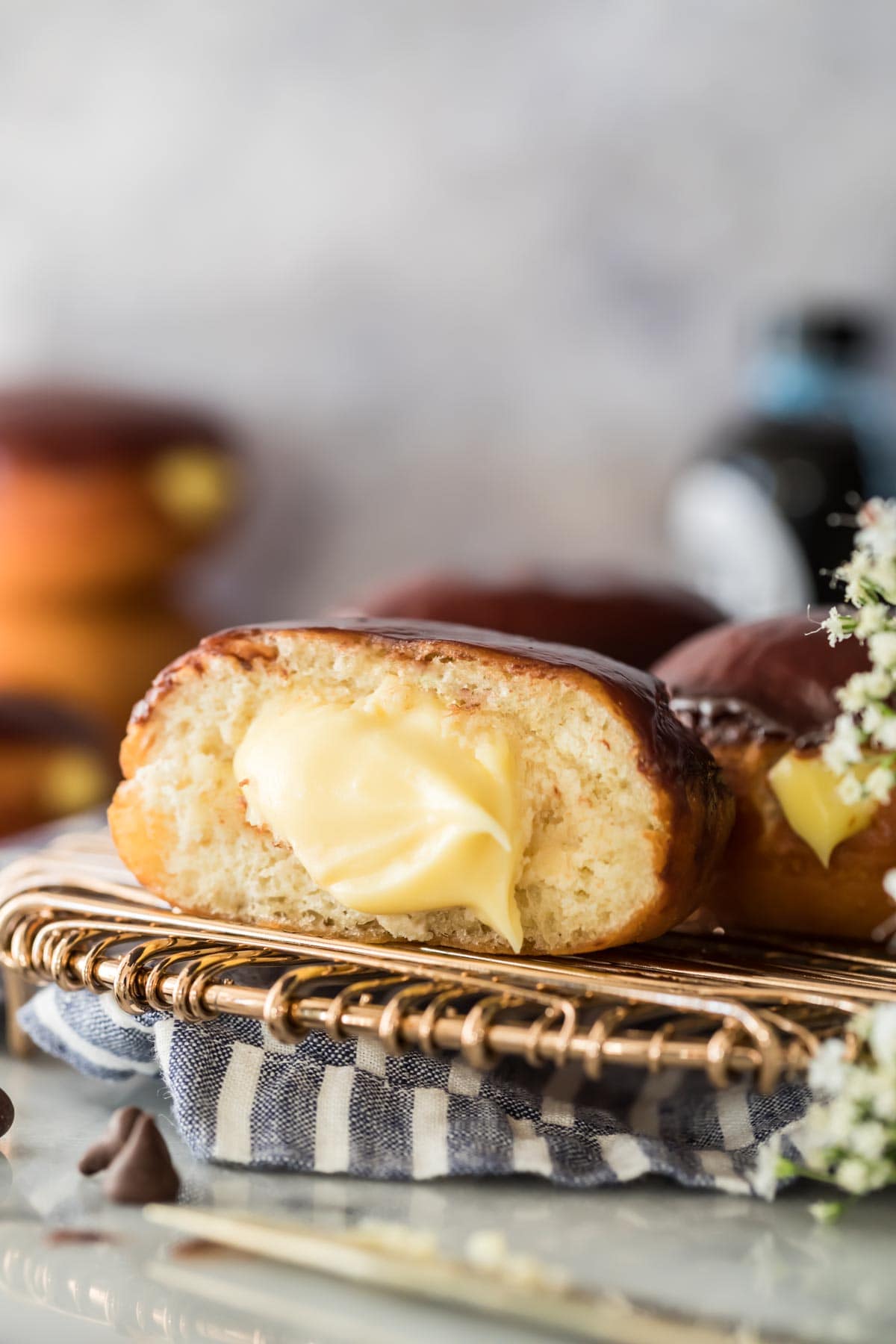 A ganache topped Boston cream donut that's been cut in half to show the pastry cream filling