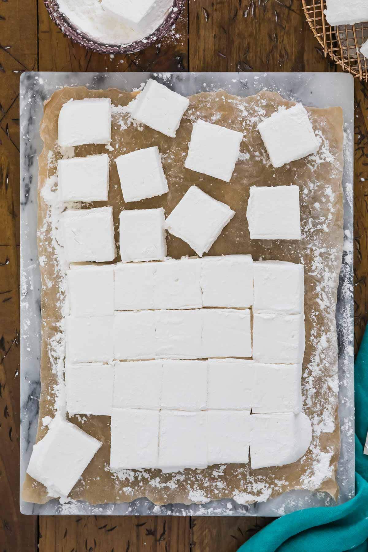 homemade marshmallows cut into squares on a marble cutting board