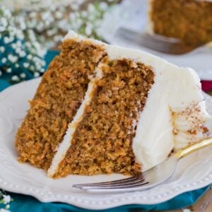 cream cheese frosted carrot cake on a white plate with one bite missing