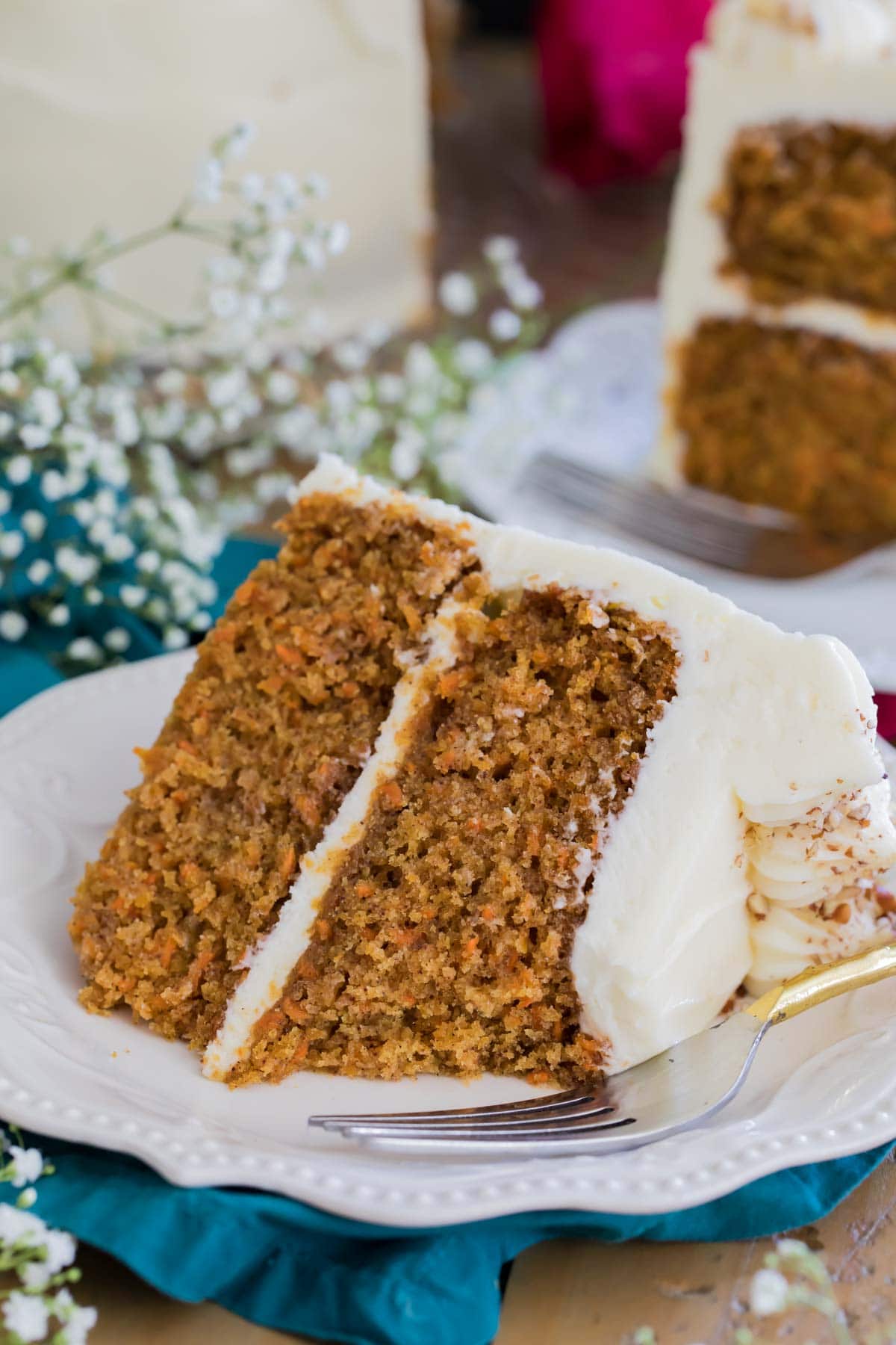 cream cheese frosted carrot cake on a white plate with one bite missing