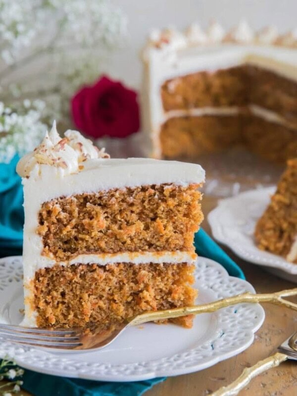 Single slice of carrot cake sitting upright on white plate