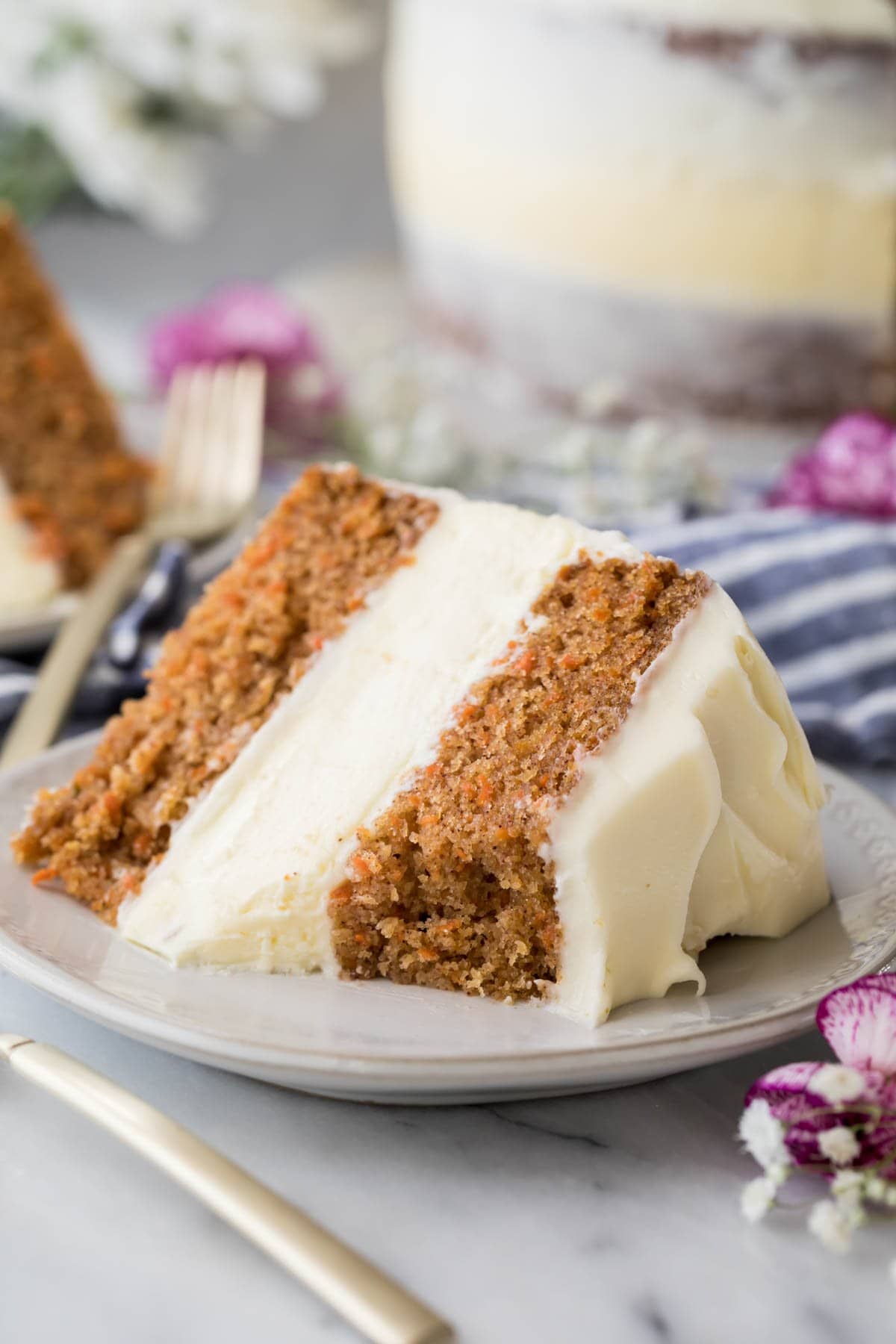 slice of carrot cake cheesecake frosted with cream cheese icing with one forkful missing