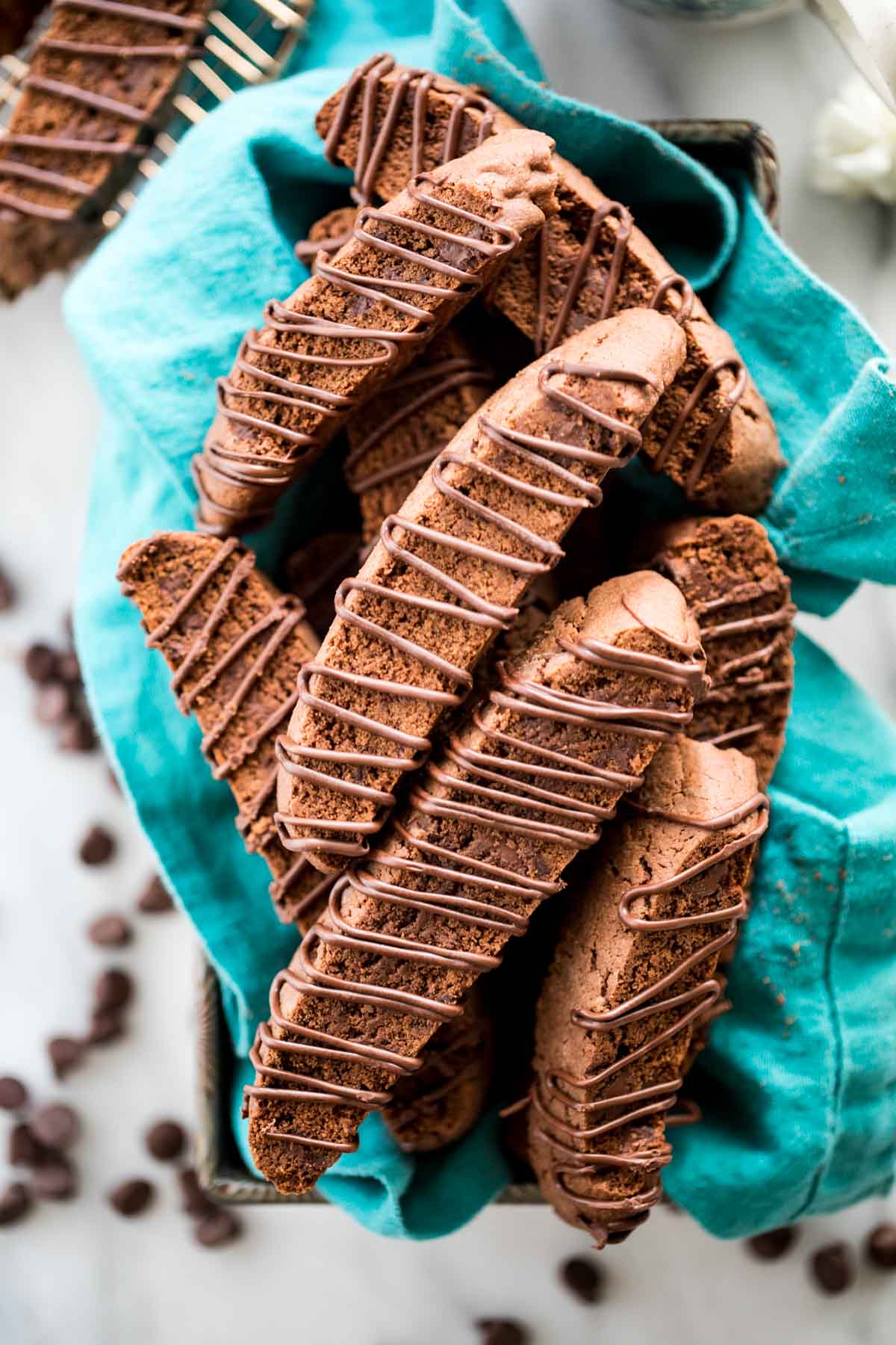 overhead view of chocolate drizzled chocolate biscotti cookies arrange on a teal towel