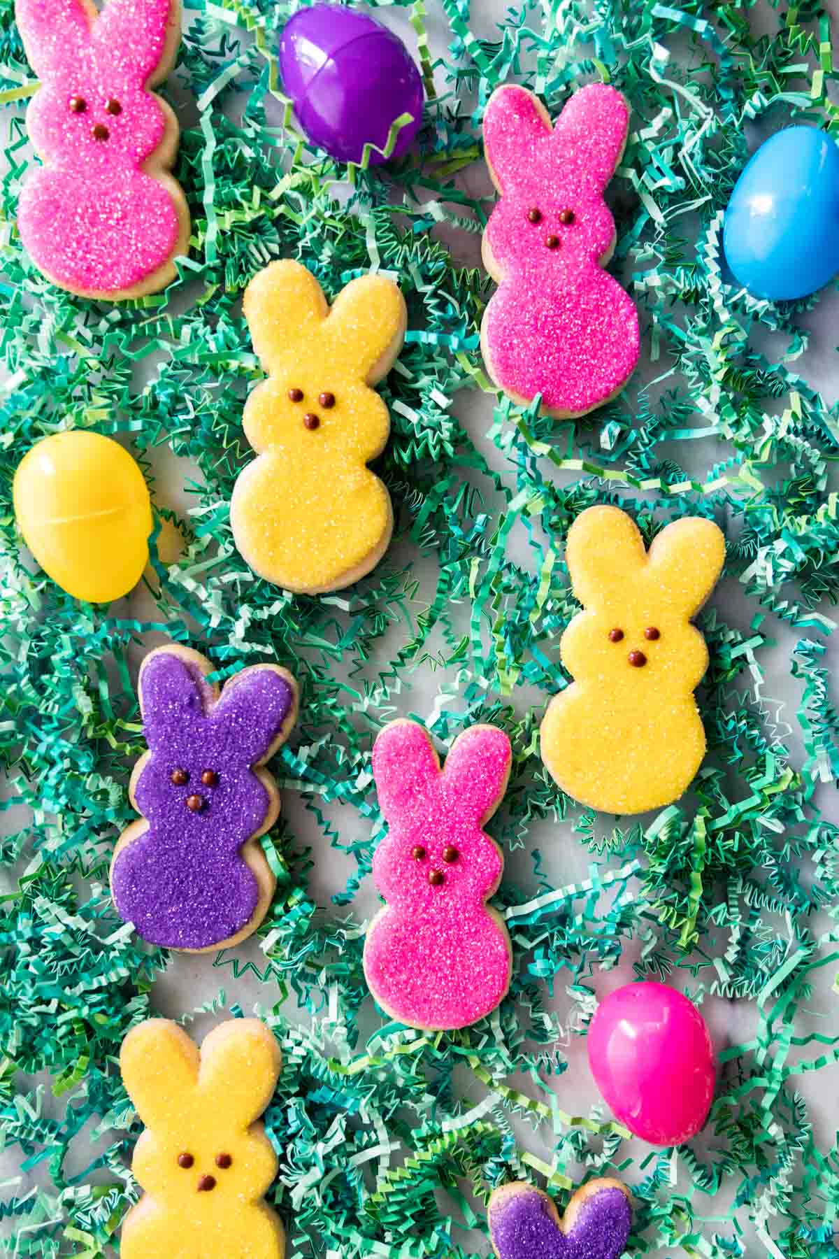 green easter grass with colorful bunny shaped sugar cookies and plastic eggs scattered throughout