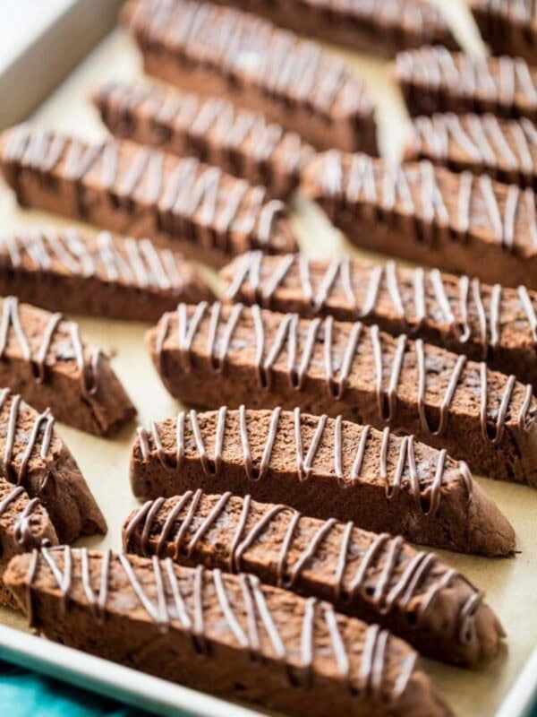 chocolate drizzled chocolate biscotti cookies arranged on a baking sheet
