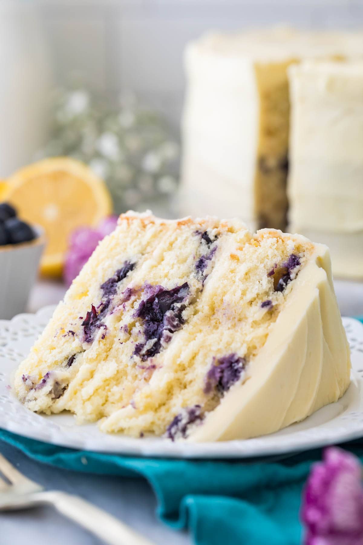 close-up view of a thick slice of lemon blueberry cake frosted with lemon frosting