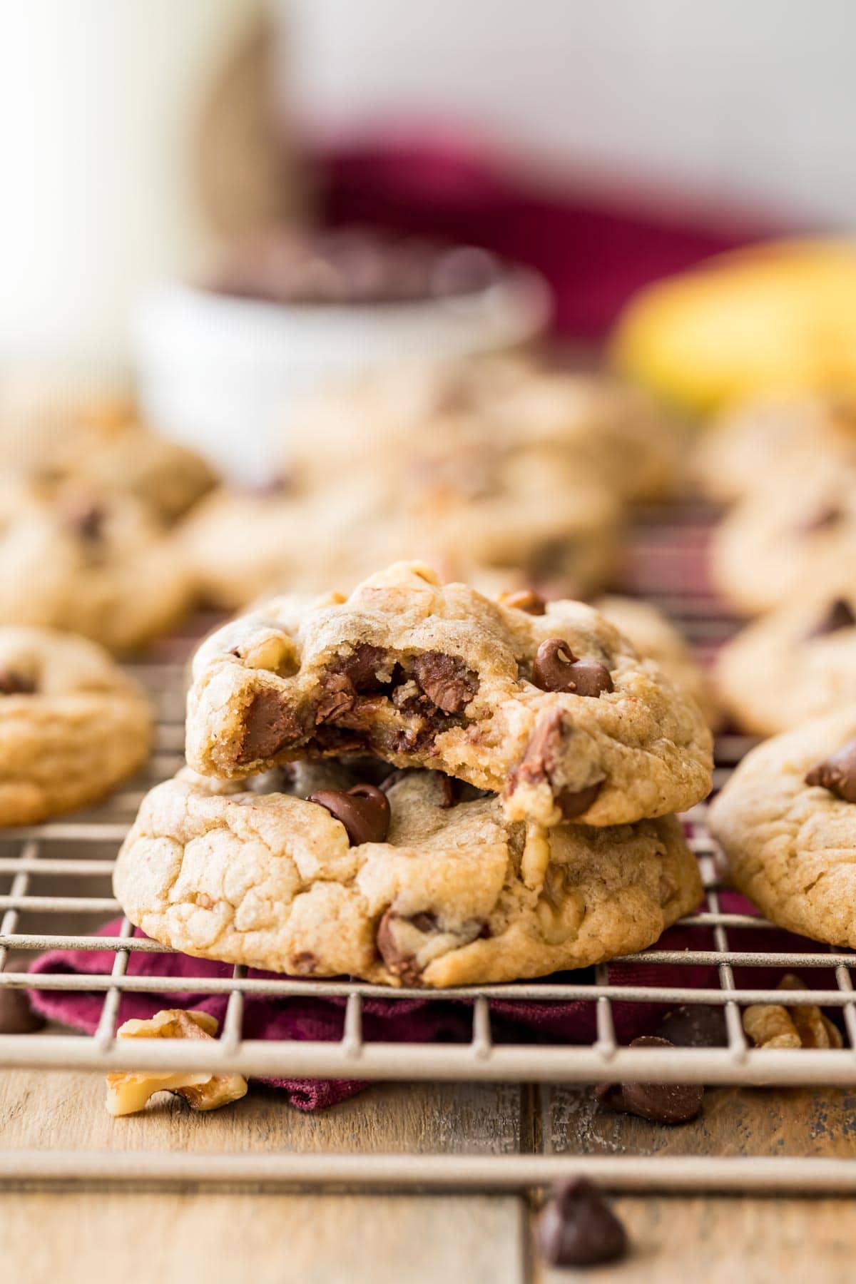 two cookies filled with chocolate chips and walnuts stacked on top of each other, with the top cookie missing a bite