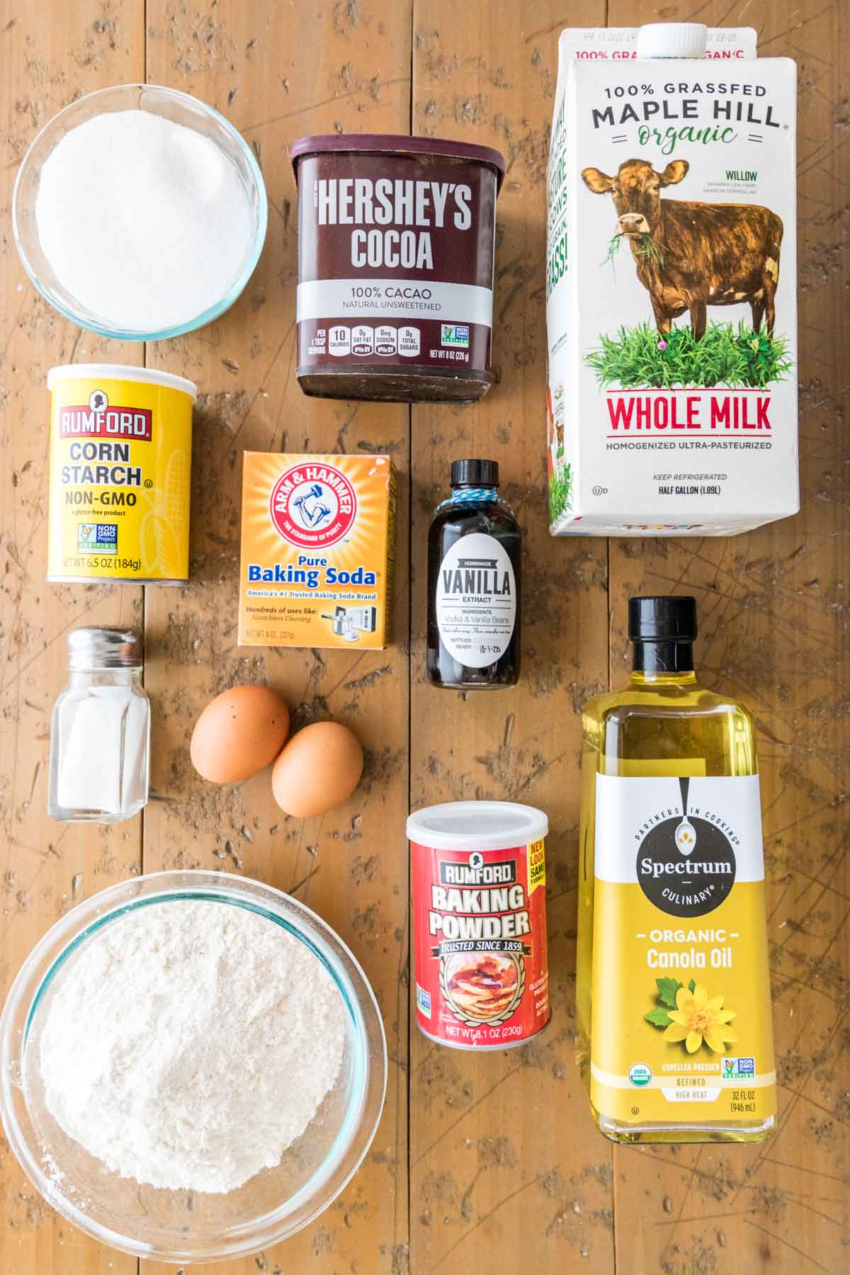 overhead view of cupcake ingredients including cocoa powder, milk, flour, eggs, and more