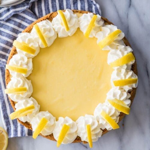 overhead view of a whole lemon cheesecake decorated with whipped cream and lemon slices
