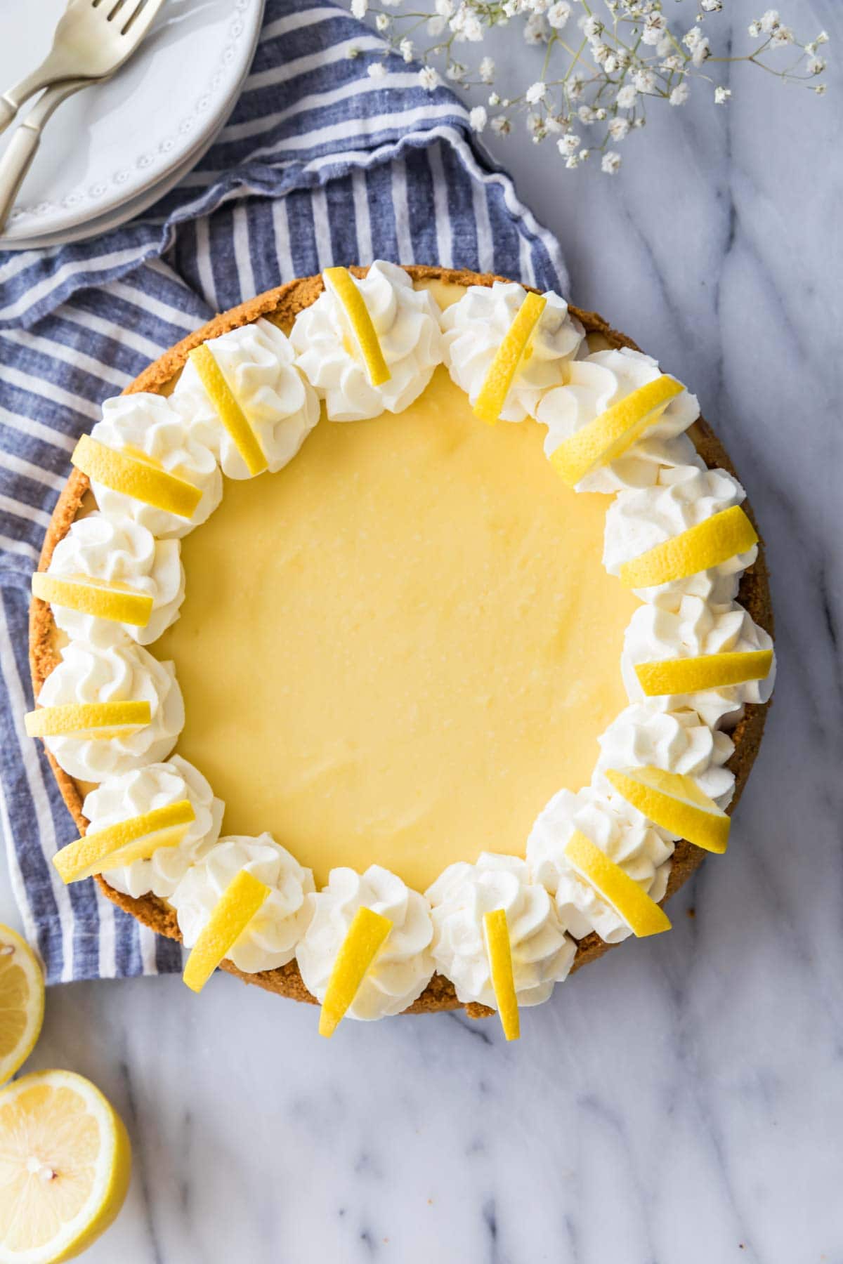 overhead view of a whole lemon cheesecake decorated with whipped cream and lemon slices