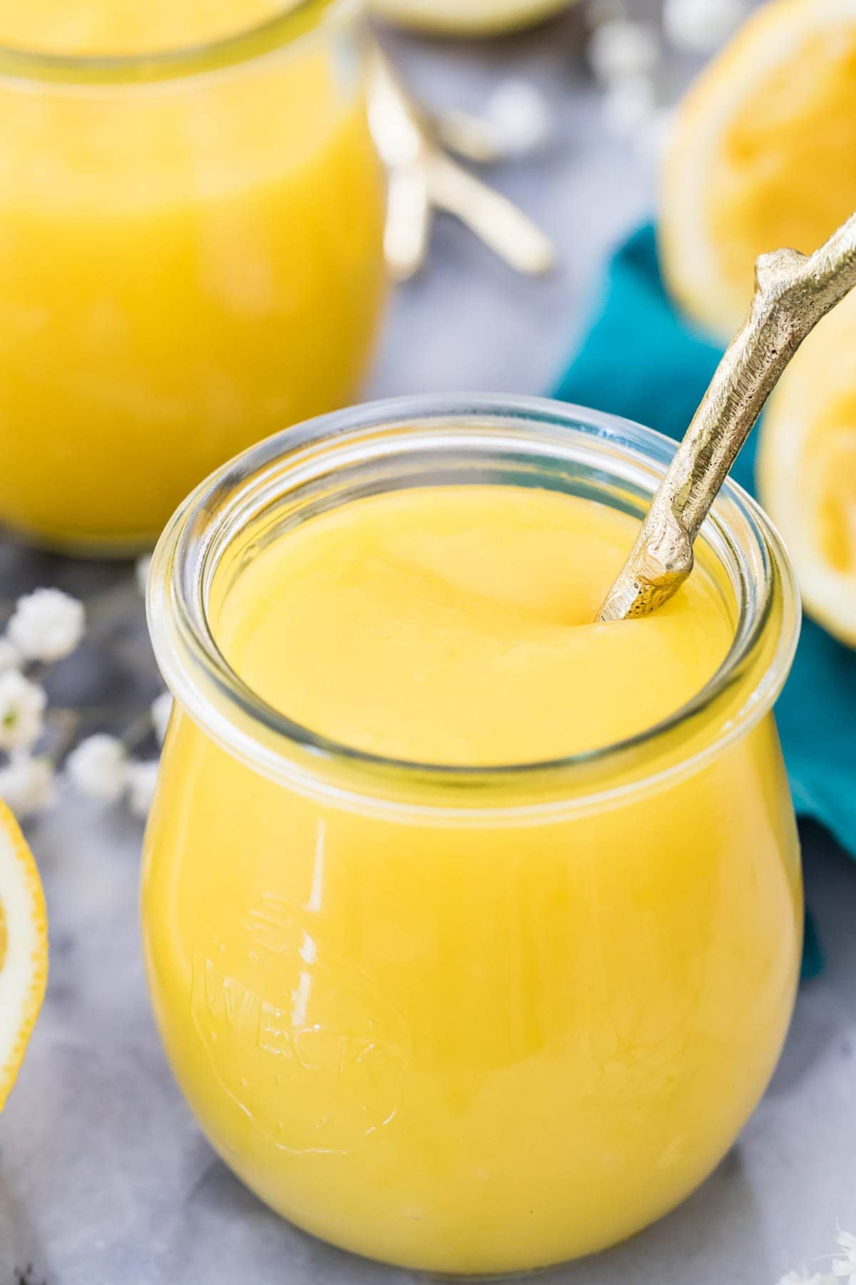 close-up view of a glass jar filled with bright yellow curd with a spoon dipped into it