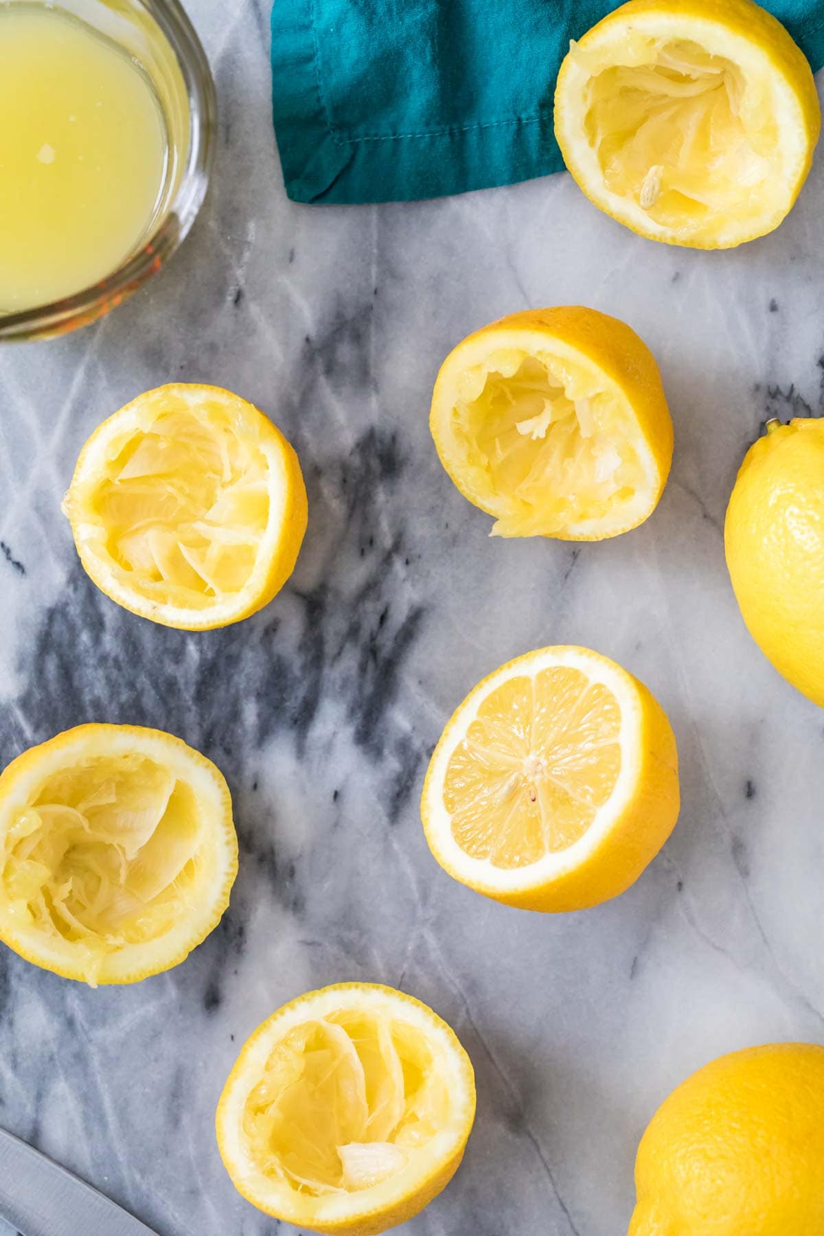 juiced lemon halves scattered on a gray marble surface