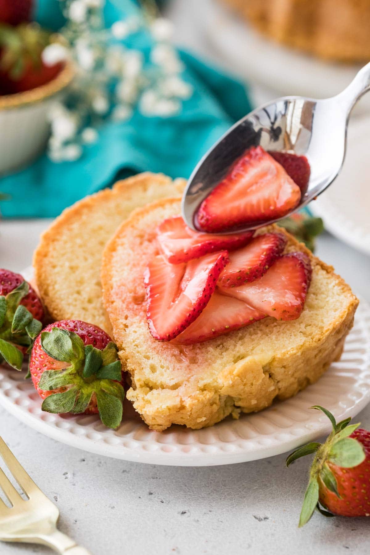 syrupy sliced strawberries being spooned onto sliced of pound cake