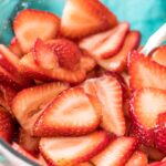 close-up shot of juicy sliced strawberries in a clear bowl