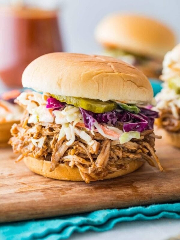 instant pot pulled pork on a sandwich topped with homemade coleslaw and pickles
