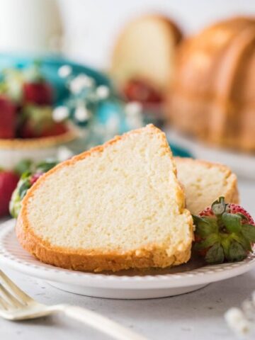 two slices of cake on a white plate with whole strawberries