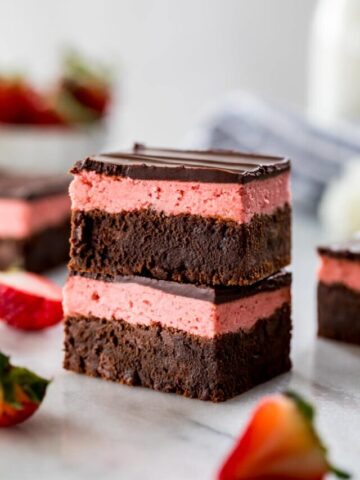 two brownie squares layered with strawberry icing and chocolate ganache stacked on top of each other