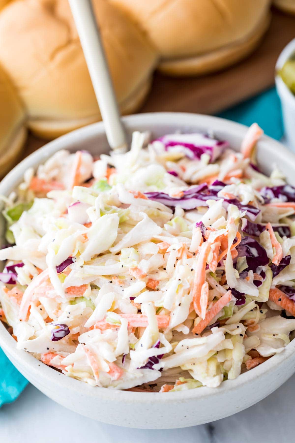 white bowl full of shredded cabbage and carrots coated in a creamy dressing