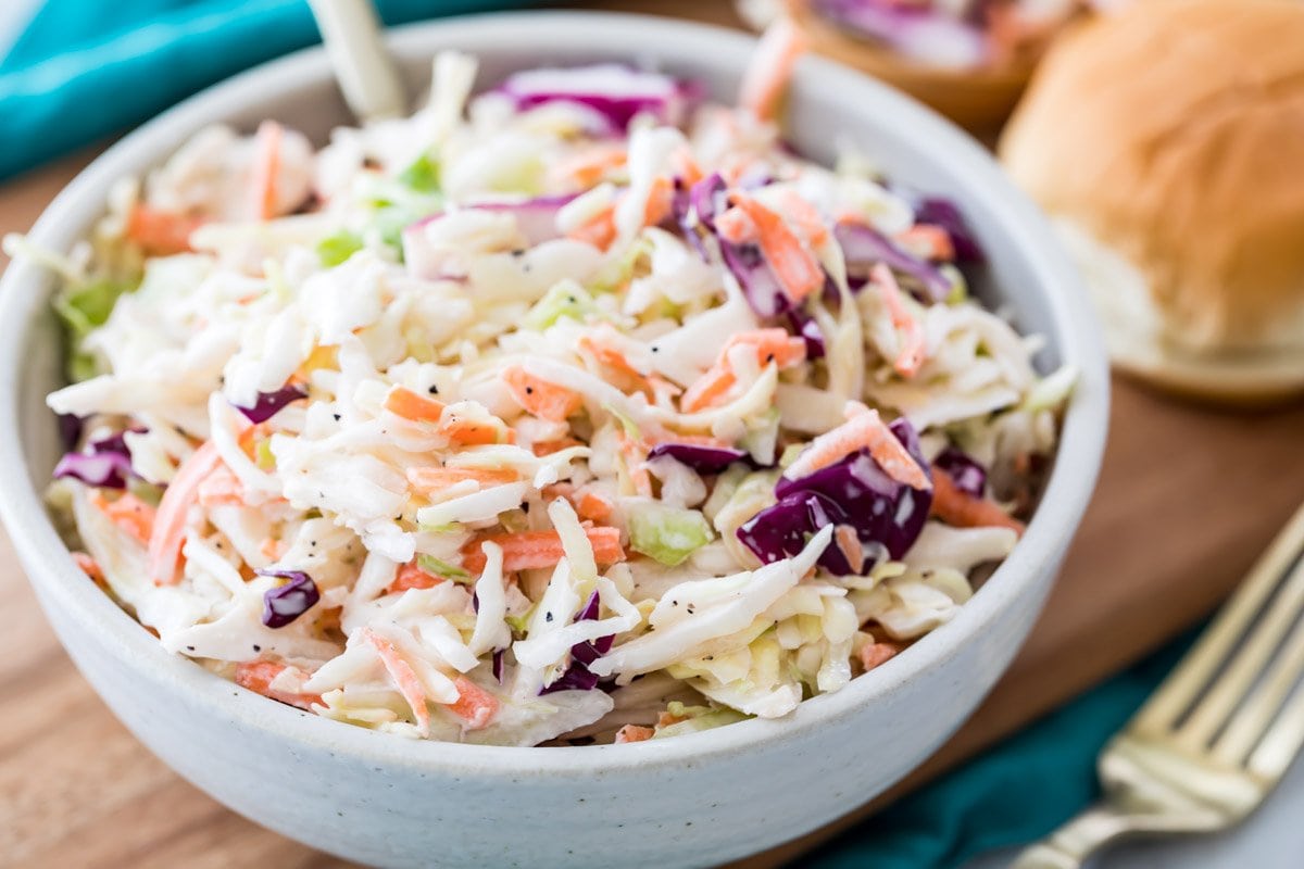 white bowl full of shredded cabbage and carrots coated in a creamy dressing