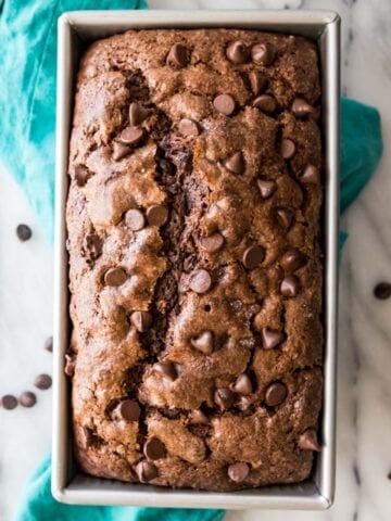 overhead view of a chocolate banana bread studded with chocolate chips in a metal loaf pan