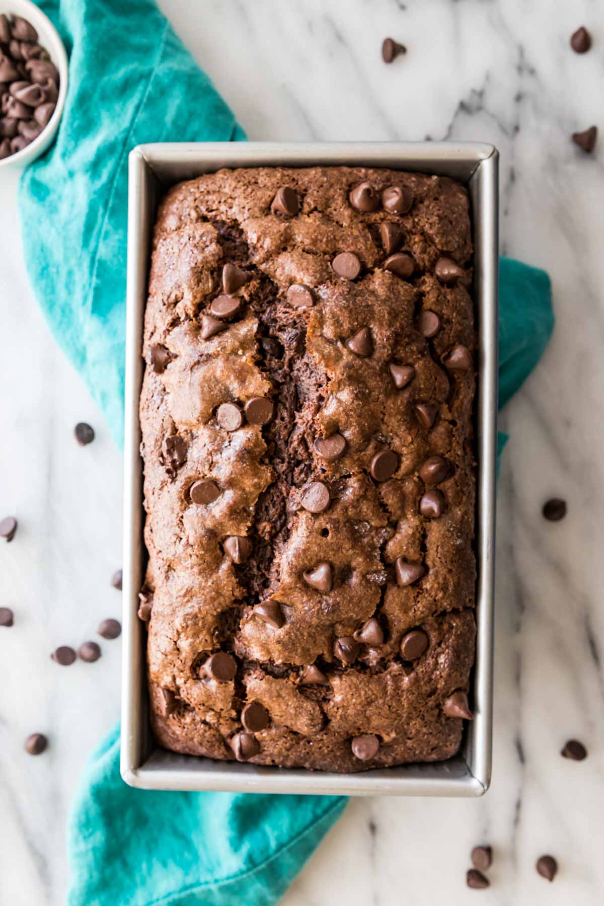 overhead view of a chocolate banana bread studded with chocolate chips in a metal loaf pan