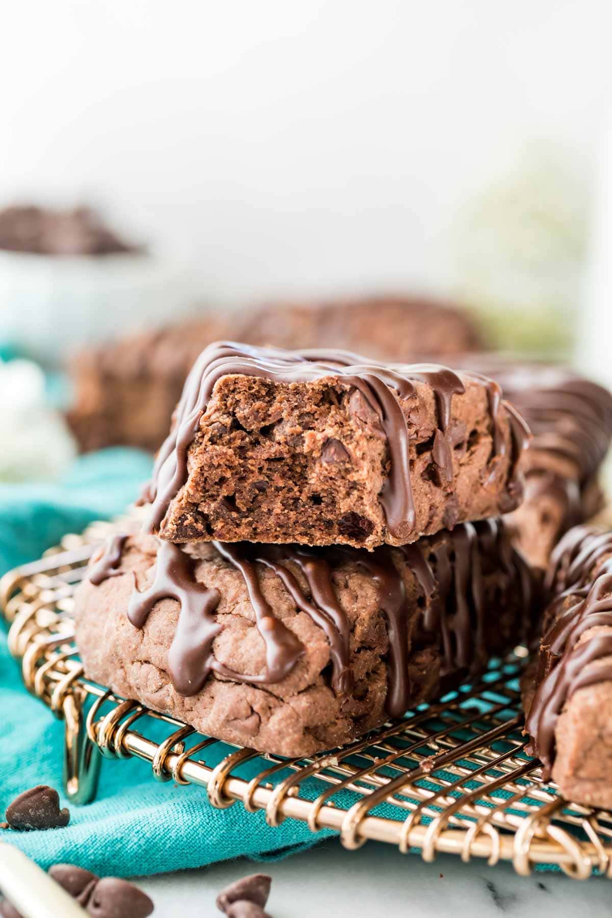 two chocolate drizzled scones stacked on top of each other, with the top scone missing a bite