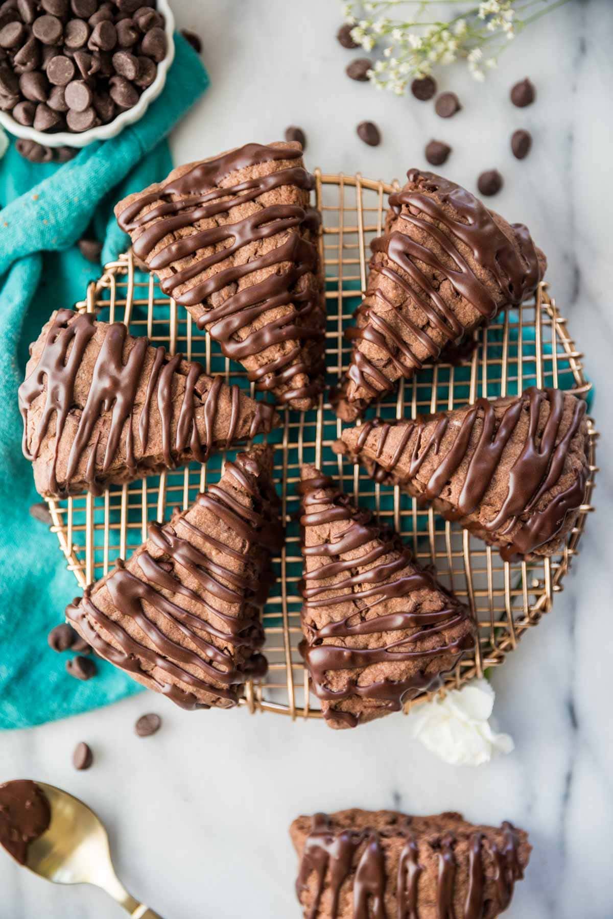 overhead view of wedge shaped scones drizzled in chocolate resting on a circular metal cooling rack