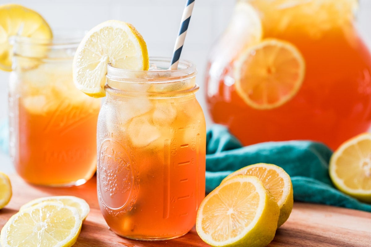 mason jars of iced tea with striped paper straws and lemon garnishes