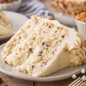 slice of italian cream cake consisting of three layers of cake studded with coconut and pecans frosted with a cream cheese frosting