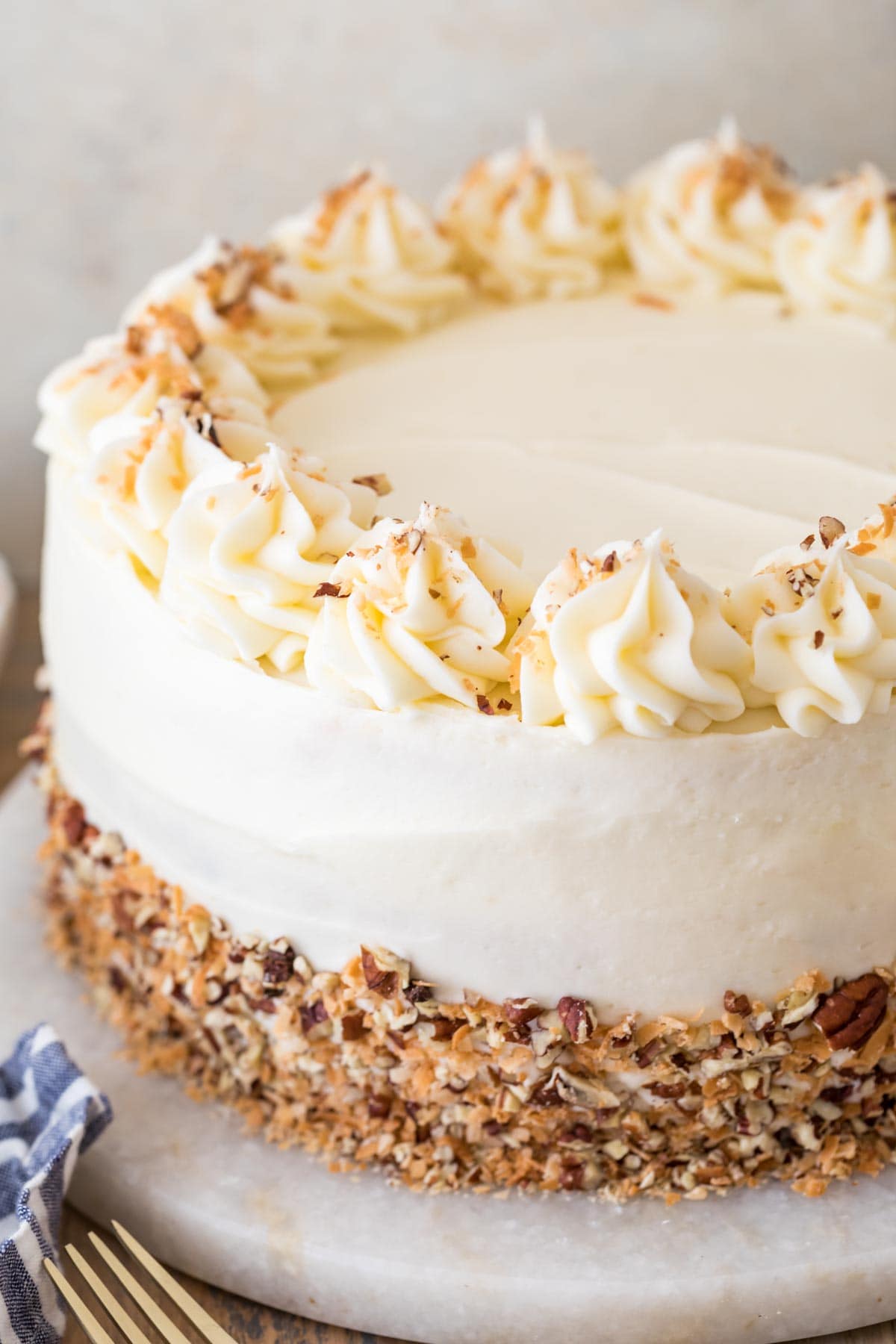italian cream cake frosted with cream cheese frosting elegantly decorated with chopped pecans and toasted coconut
