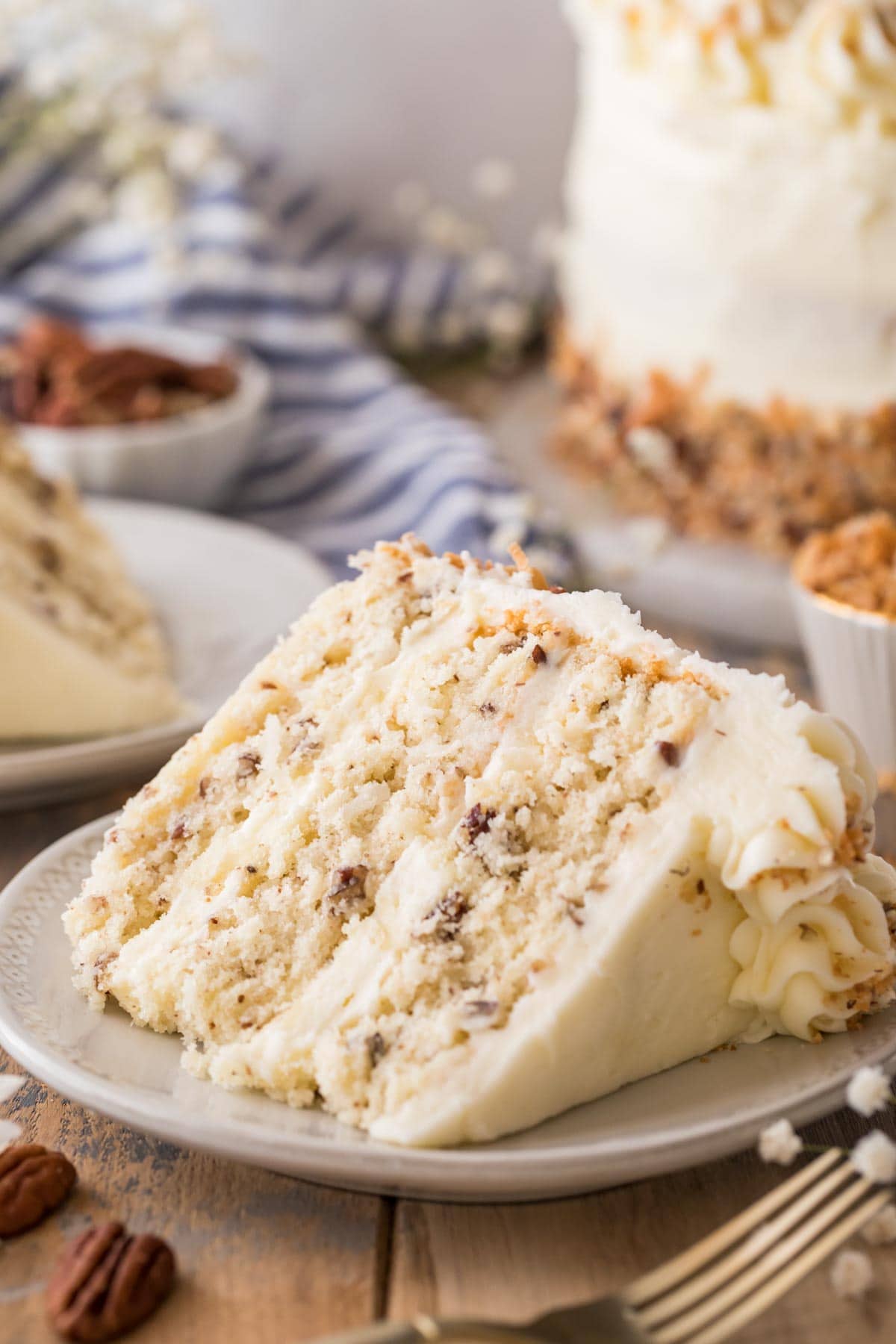 slice of italian cream cake consisting of three layers of cake studded with coconut and pecans frosted with a cream cheese frosting