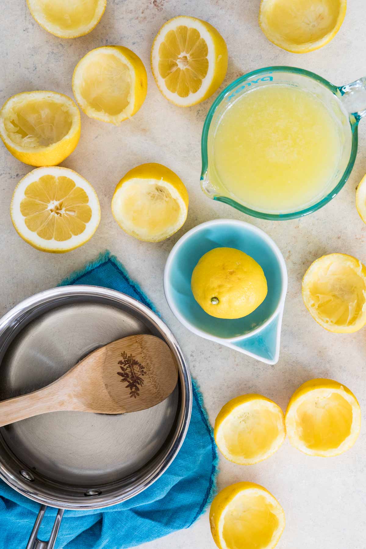 overhead view of lemon halves being juiced into a glass measuring cup