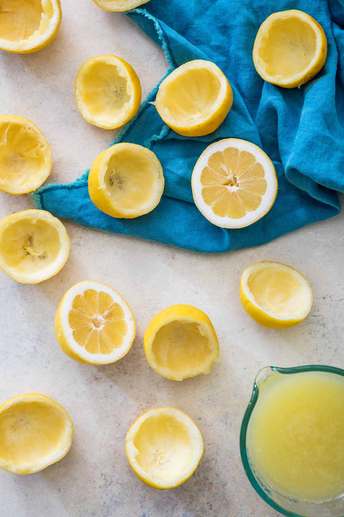 juiced and unjuiced lemon halves scattered on a white counter