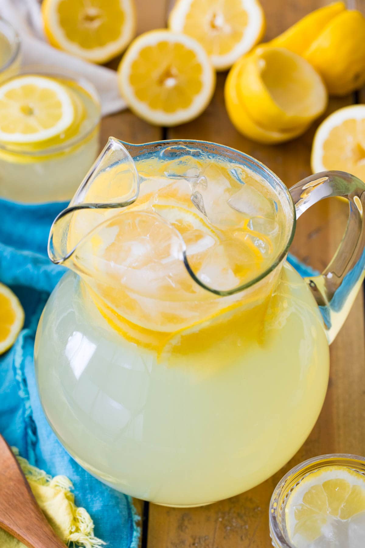 glass pitcher of homemade lemonade surrounded by lemon halves