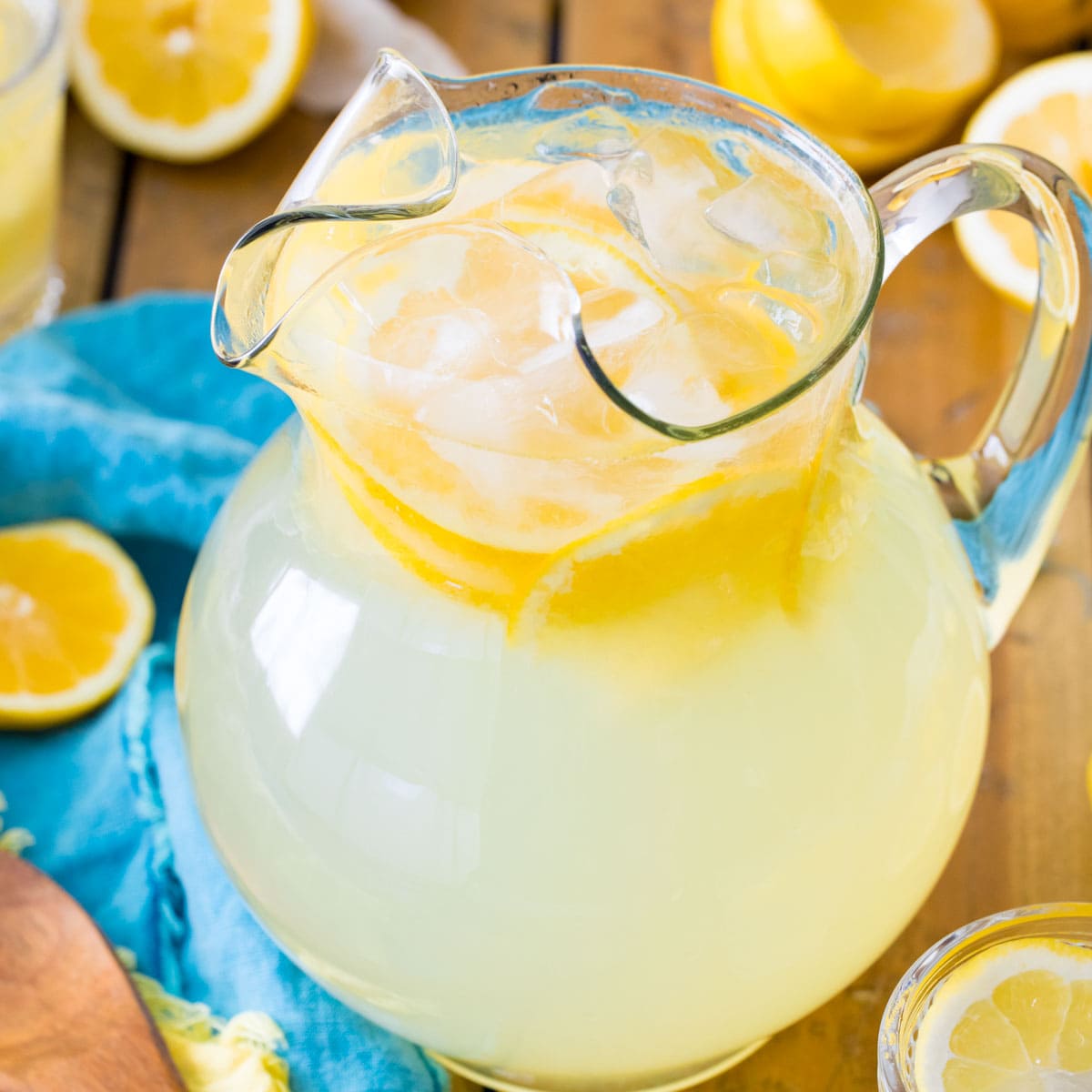 glass pitcher of homemade lemonade surrounded by lemon halves
