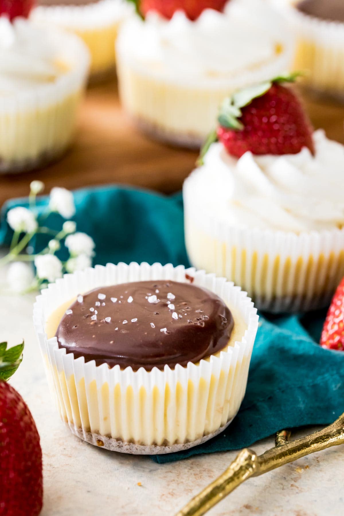 small, individual cheesecake served in a cupcake liner topped with chocolate ganache and sea salt